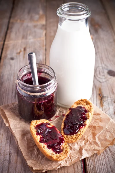 Black currant jam in glass jar, milk and crackers — Stock Photo, Image