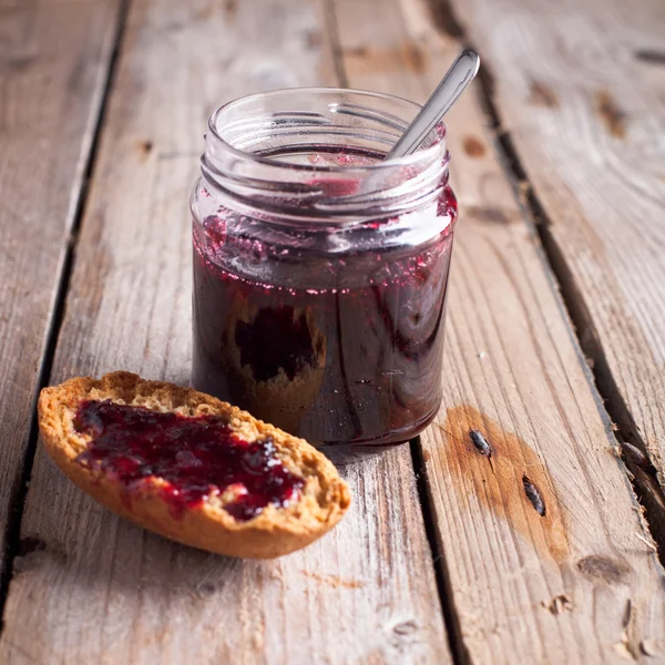 Black currant jam in glass jar and cracker — Stock Photo, Image