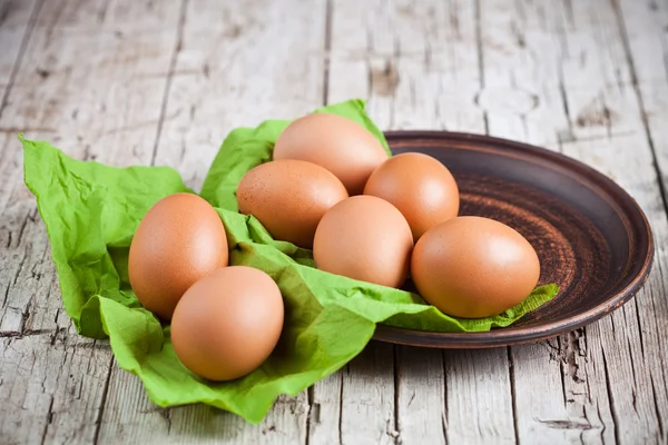 Frische braune Eier in Teller und grüner Serviette — Stockfoto