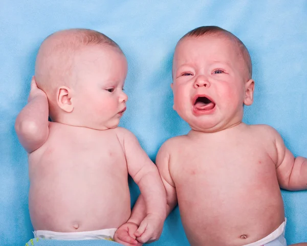 Дві солодкі немовлята: одна дивиться, одна плаче — стокове фото