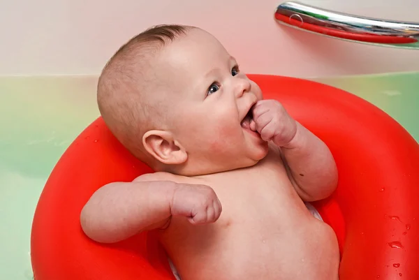 Het jonge geitje zwemt in de grote badkamer op een rode leven boei — Stockfoto