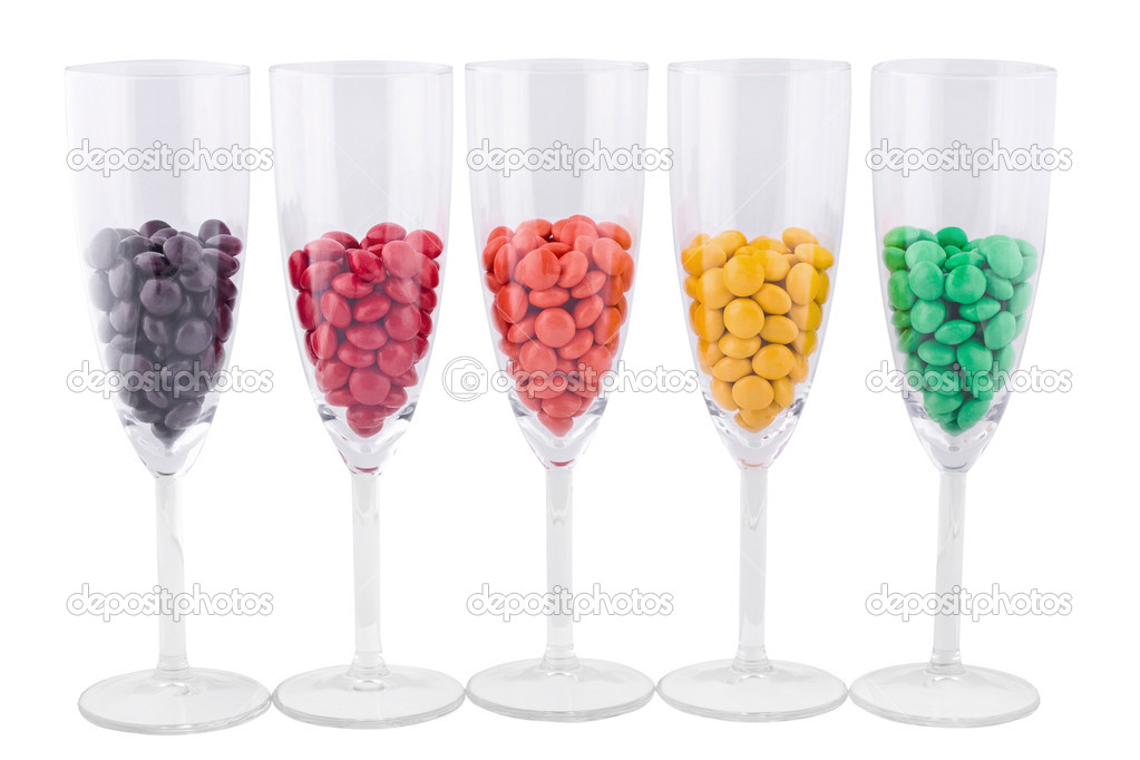 Five wine glasses with a color dragee on the white