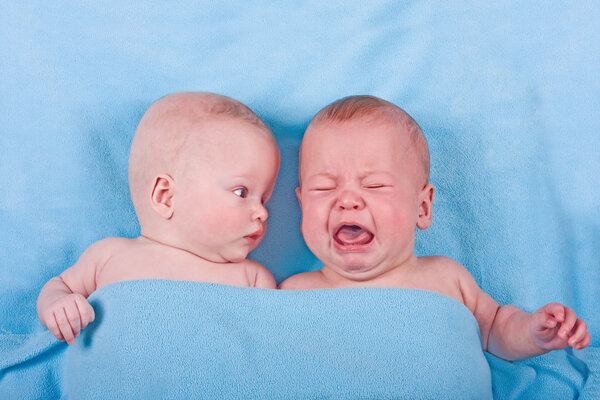 Два милых младенца - один смотрит, другой плачет
