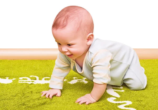 A criança se arrasta em um tapete verde macio isolado — Fotografia de Stock