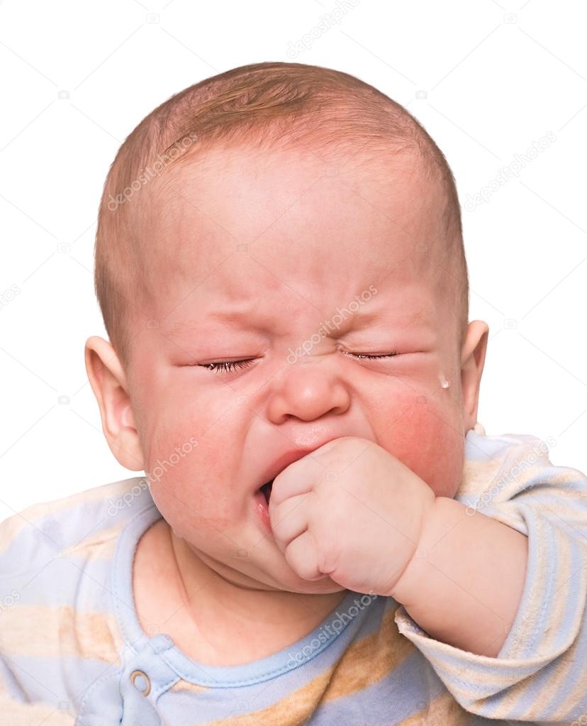 The crying boy in tears, hand in mouth, on white background