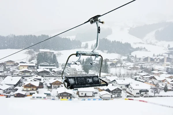 Skilift stoelen tegen van kirhberg, Oostenrijk. sneeuwval — Stockfoto