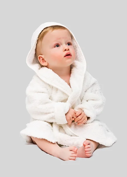 Le gamin d'un an en robe de chambre blanche sur un backgrou gris — Photo