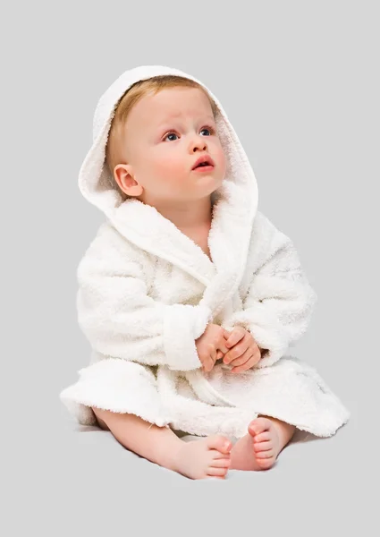 The one-year-old kid in a white dressing gown on a gray background — Stock Photo, Image
