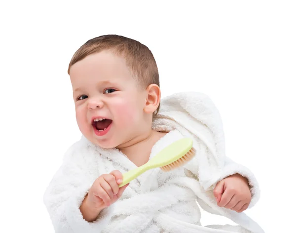 A criança de um ano rindo em um vestido de vestir branco com uma escova de cabelo em uma mão — Fotografia de Stock