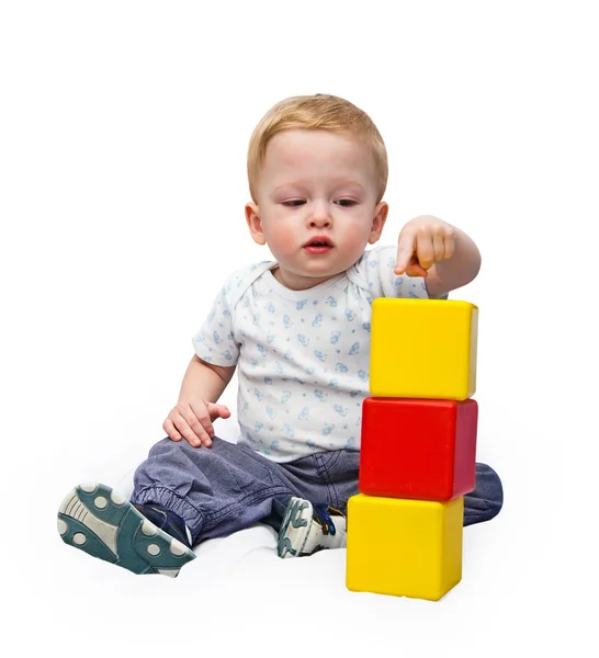 The child builds a pyramid of cubes on the white — Stock Photo, Image