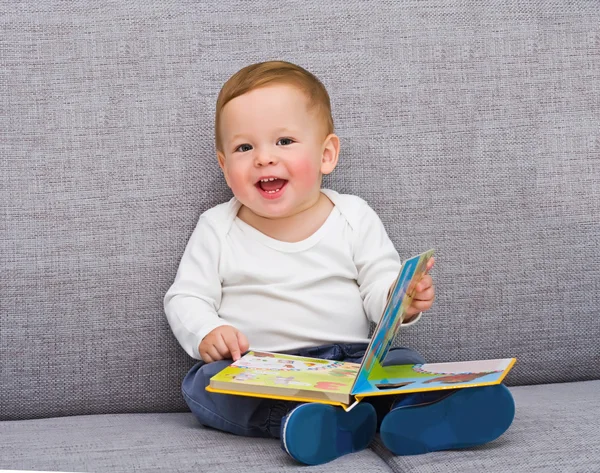 Das einjährige Kind sitzt mit dem Buch lizenzfreie Stockfotos