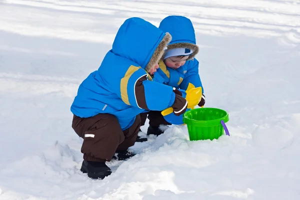 One-year-old twins play in snow together Stock Image