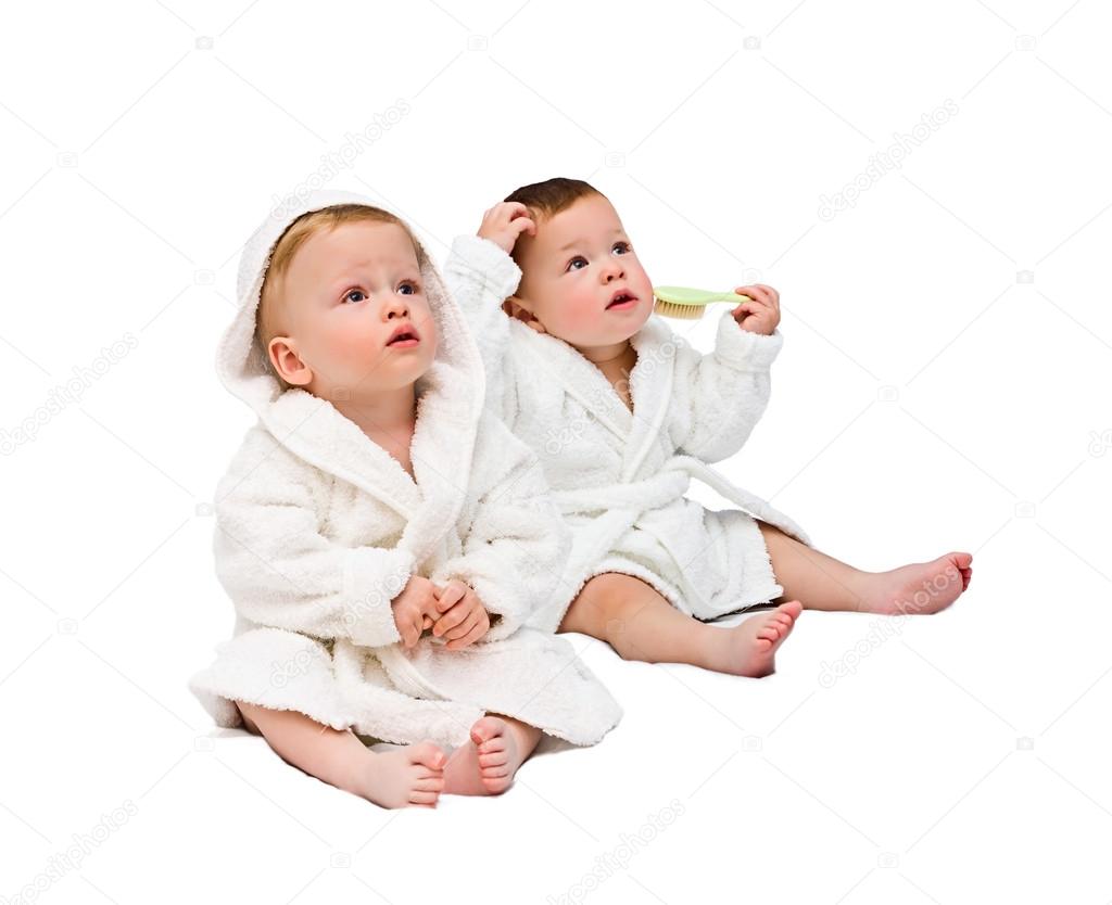 One-year-old twins in dressing gowns on a white background
