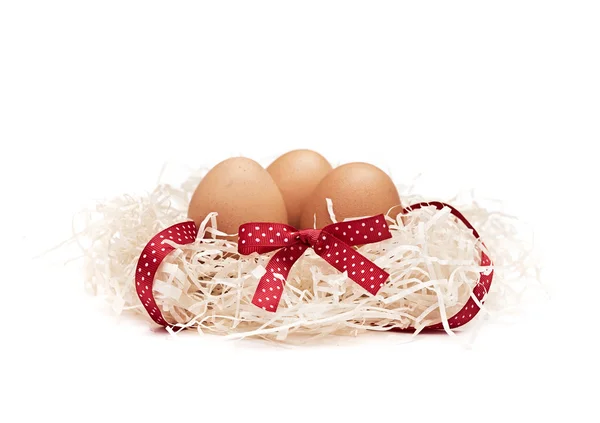 Три коричневых яйца в гнезде с бантом на конце ленты — стоковое фото