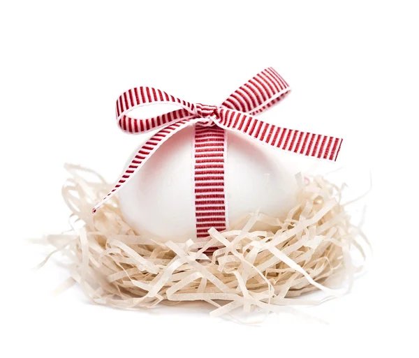 Białych jaj w gnieździe z czerwoną wstążką i łuk — Zdjęcie stockowe