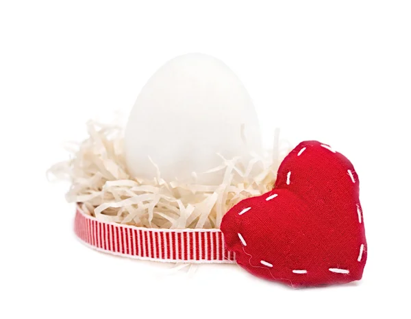 Œuf blanc dans un nid avec ruban rouge, coeur — Photo