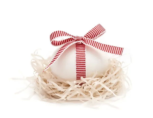 White egg in a nest with red ribbon and bow — Stock Photo, Image