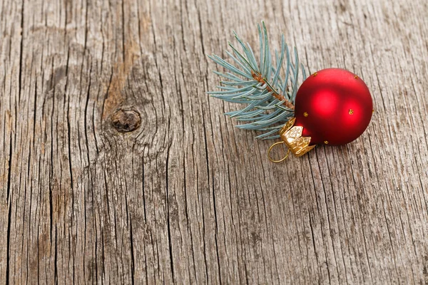 Rote Weihnachtskugel auf hölzernem Hintergrund mit Tannenzweig — Stockfoto