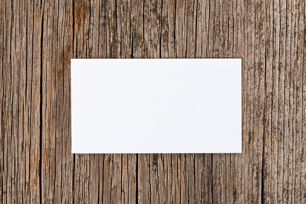 Empty white card over old textured wooden background