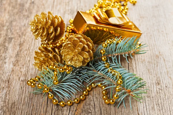 Decorazioni natalizie dorate su ramo di pino su fondo di legno — Foto Stock
