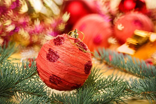 Bola de decoração vermelha com ramo de abeto no bac de Natal borrado — Fotografia de Stock