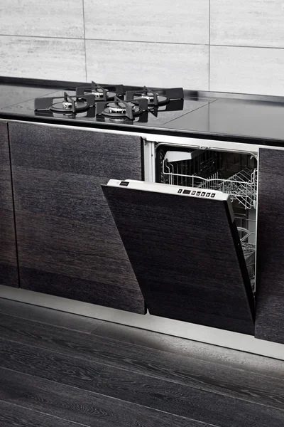 Open dish washer machine and gas-stove on black hardwood kitchen — Stock Photo, Image