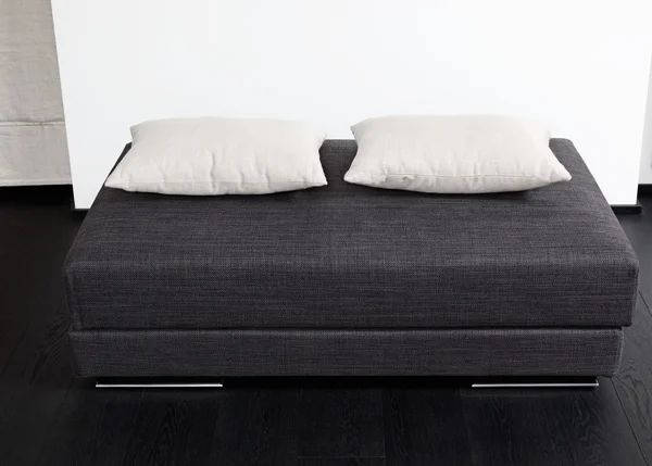 Taburete acolchado gris oscuro con almohada blanca, detalle del interior moderno de la sala de estar en blanco y negro — Foto de Stock