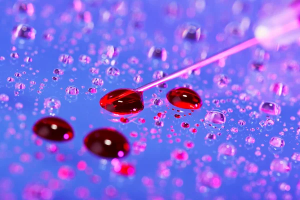 Aiguille de seringue avec gouttes de liquide (sang) sur gouttelettes d'eau backgr — Photo