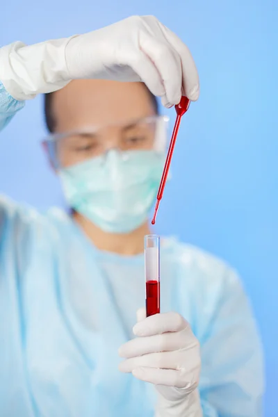 Mujer joven médico haciendo análisis de sangre con tubo de ensayo y gota — Foto de Stock