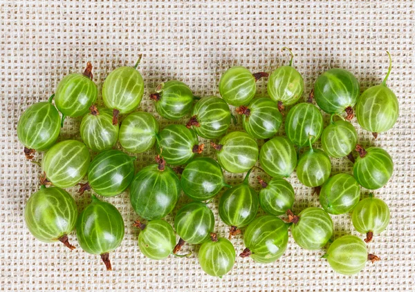 Molti frutti di uva spina su tovaglia di lino grigio con spazio copia — Foto Stock