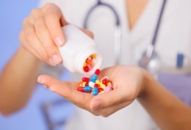 Pills, tablets and drugs pouring from bottle in doctor's hand on clipart