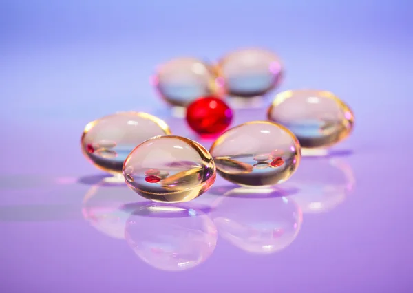 Pilules (capsules) d'huile de foie de morue sur violet, vue macro avec sel — Photo