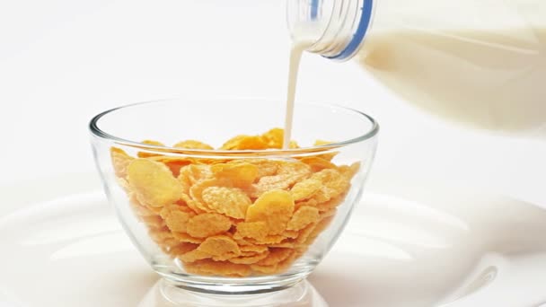 Corn flakes in a glass bowl pouring with milk — Stock Video