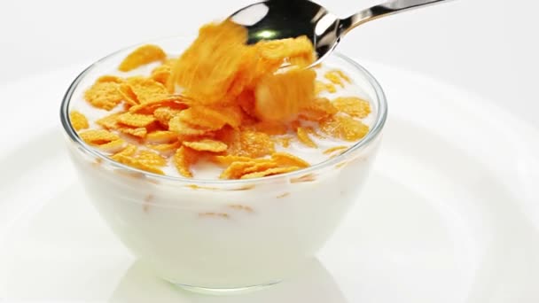 Kochen von Cornflakes mit Milch in einer Glasschüssel, die mit einem Löffel umgerührt wird — Stockvideo