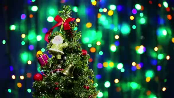 Geschmückter Weihnachtsbaum dreht sich auf blinkendem mehrfarbigem Bokeh-Hintergrund — Stockvideo