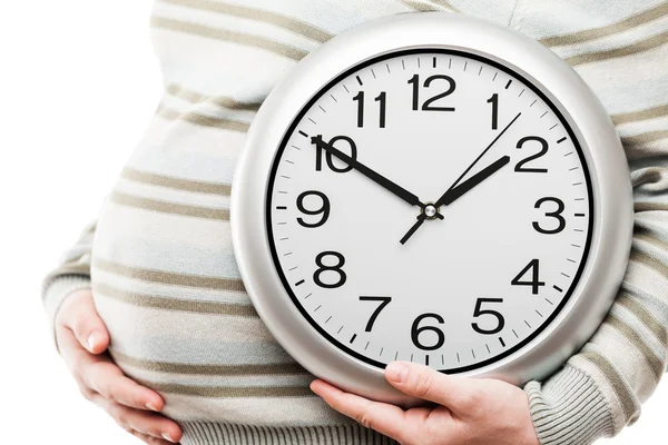 Embarazada mujer mano celebración de gran reloj de pared de oficina que muestra el tiempo —  Fotos de Stock