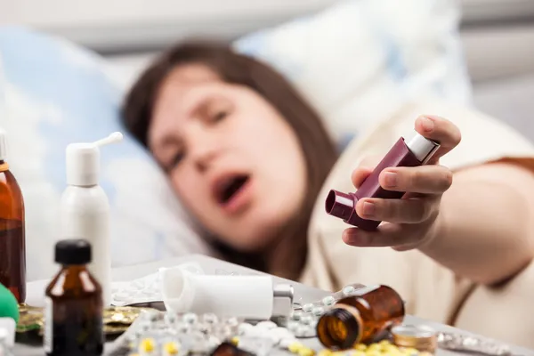 Mulher paciente na cama mão segurando inalador asmático — Fotografia de Stock