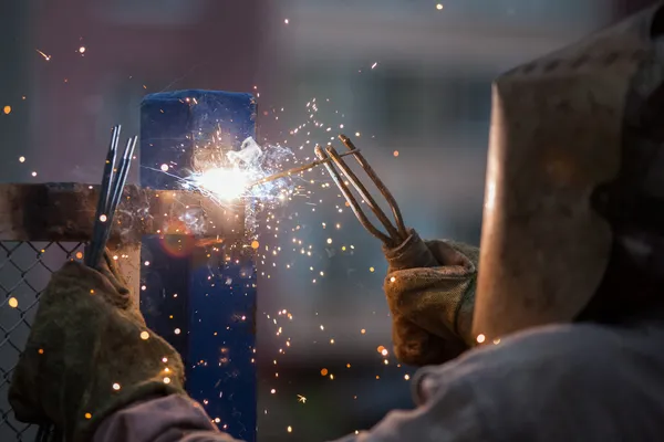 Soldador de arco trabajador en la construcción de metal de soldadura máscara protectora —  Fotos de Stock