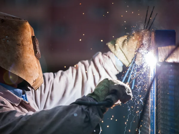 ARC svářeč dělník v ochranné masce svařování kovových konstrukce — Stock fotografie