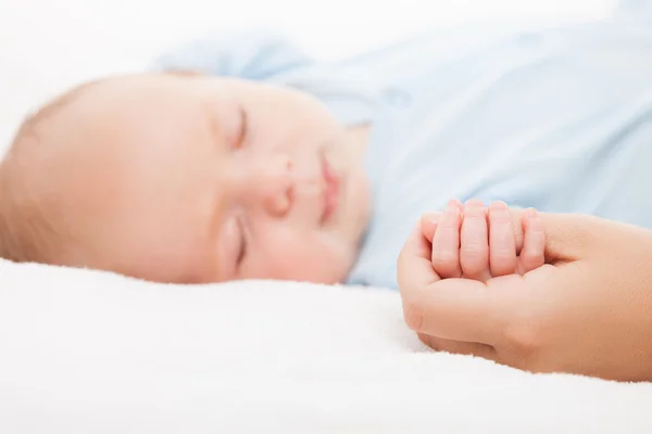 Милый спящий новорожденный ребенок держит мать за руку — стоковое фото