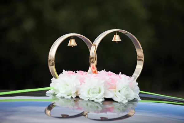 Zlaté prsteny a růžové květiny na svatební auto — Stock fotografie