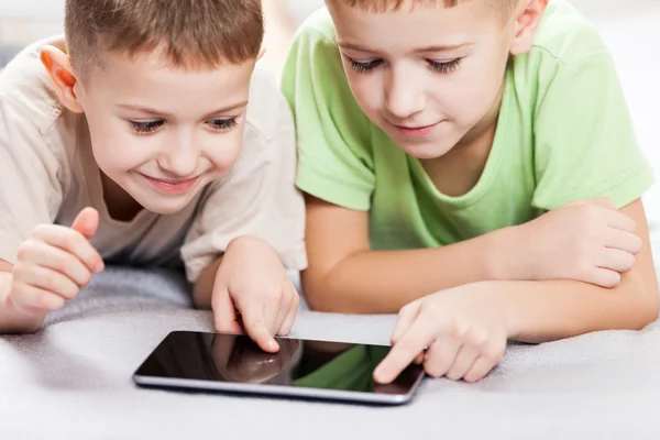 Two smiling child boys playing games or surfing internet on tabl — Stock Photo, Image