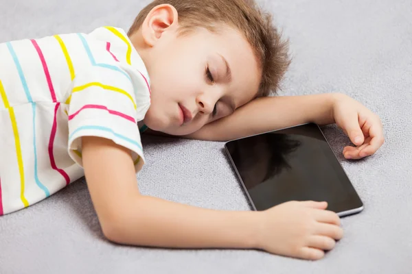 Cansado durmiendo niño sosteniendo tableta ordenador — Foto de Stock