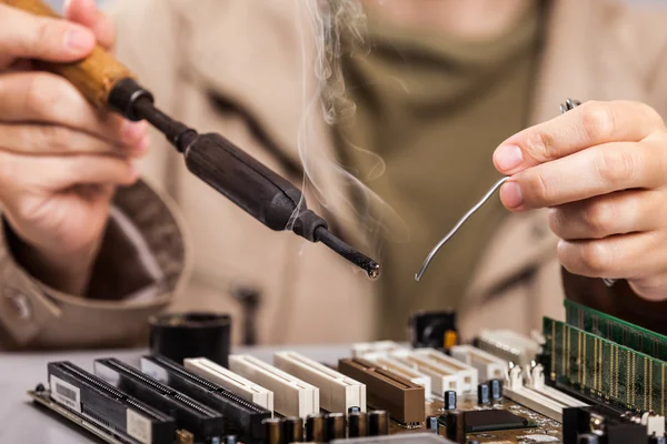 Human hand holding soldering iron repairing computer circuit boa — Stock Photo, Image