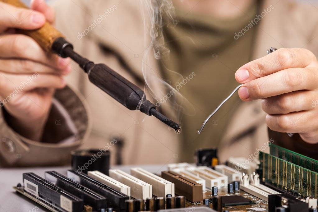 Human hand holding soldering iron repairing computer circuit boa - Stock Ph...