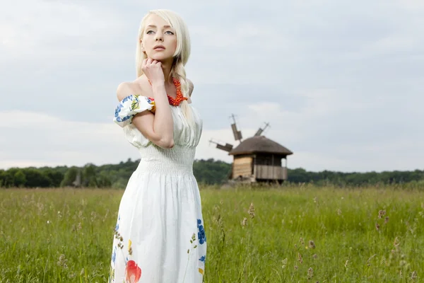 Unga landsbygdens kvinna som står på det gröna fältet — Stockfoto