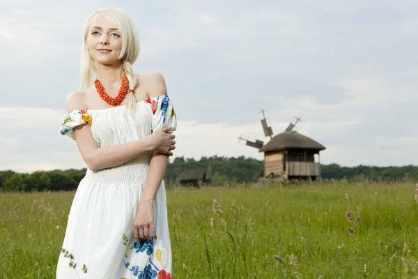 Молода сільська жінка стоїть на зеленому полі — стокове фото