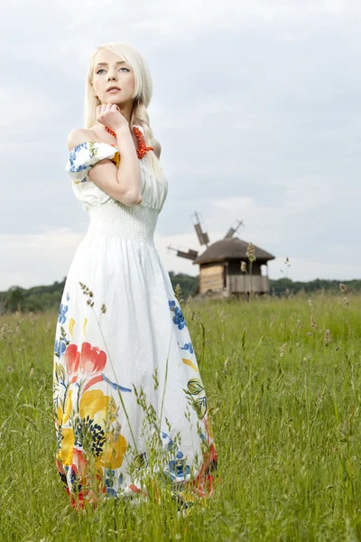 Mujer joven rural de pie en el campo verde — Foto de Stock