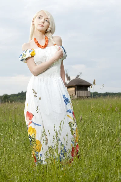 Jovem mulher rural de pé no campo verde — Fotografia de Stock