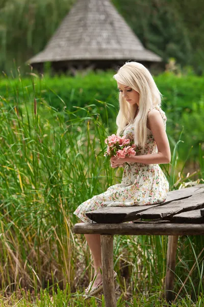 Niña sentada en un banco de madera junto al lago — Foto de Stock